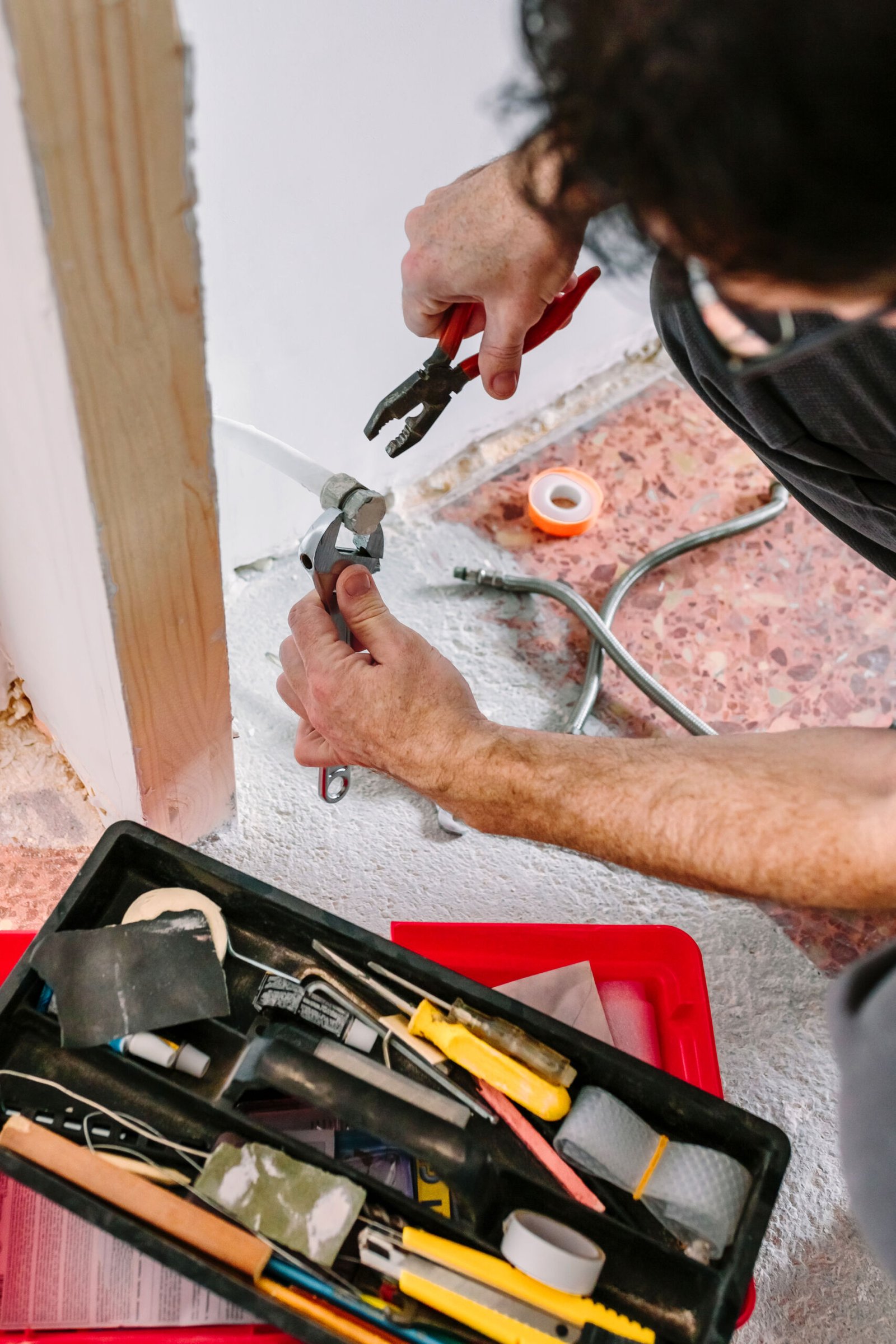 Fontanero apretando tubería con llave y alicates en instalación de calefacción